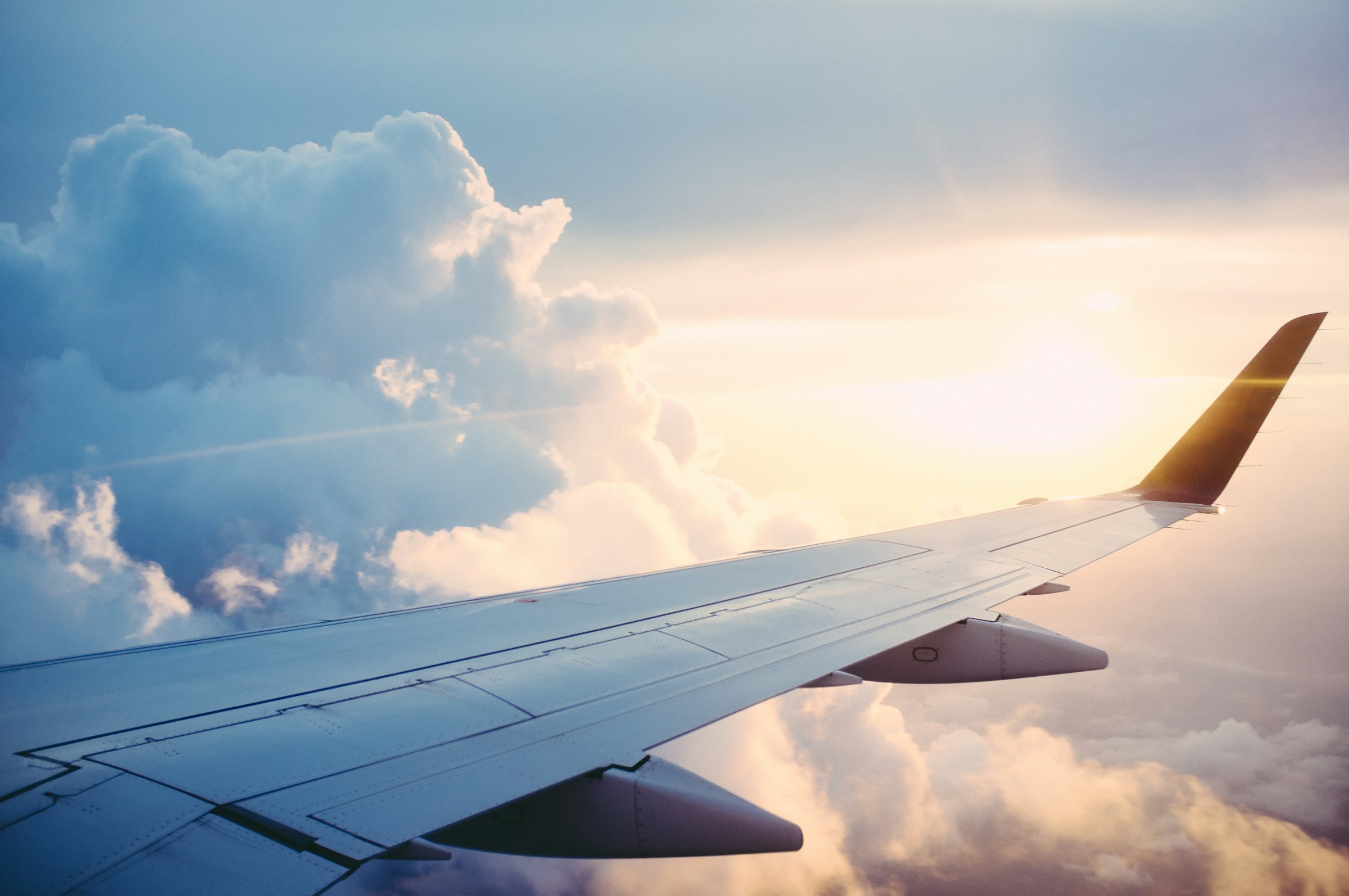 Airliner wing above the clouds at sunset